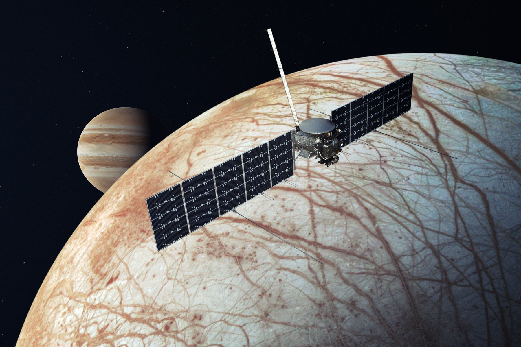 The Europa Clipper spacecraft has a box-like center with rectangular solar panels extending from either side like wings. It's shown flying above Europa with Jupiter visible in the distance.
