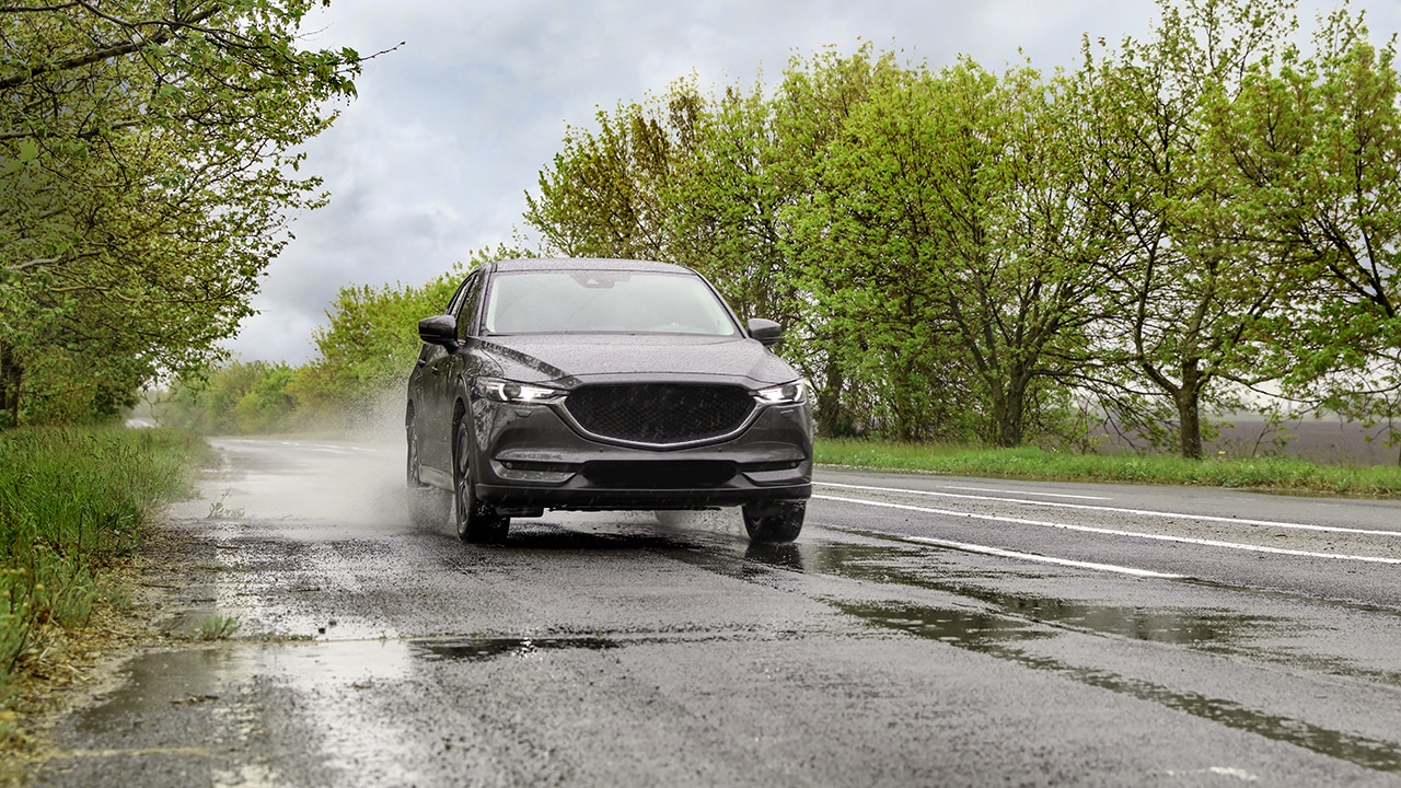 Wet suburban road with car on rainy day