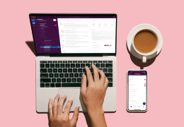 a laptop opened with Slack and someone typing with a mobile phone and coffee