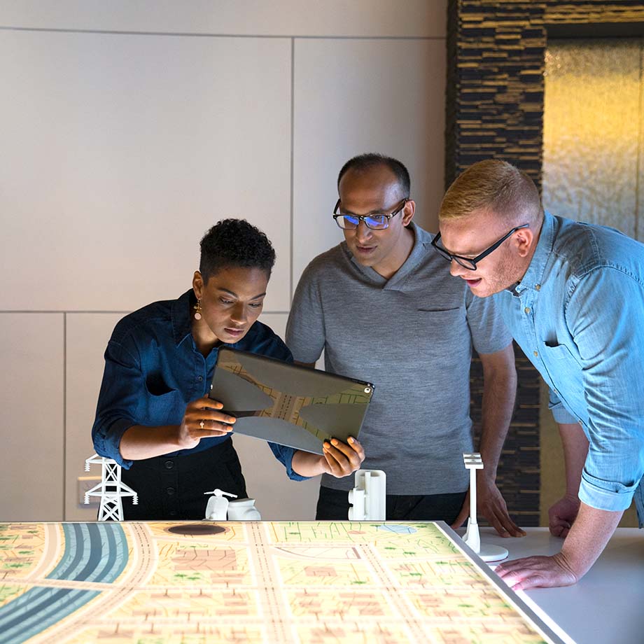 Three Verizon employees collaborating around a tablet