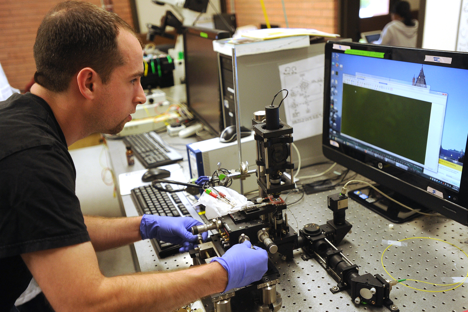 Graduate student Benjamin Gross, 31, manipulates a laser as he watches bacteria cells on a computer screen at the University of Southern California. Scientists at USC are doing basic research to determine how certain bacteria are able to transfer electrons great distances from themselves to other cells or inorganic minerals. Photograph by Kent Treptow for PBSNewsHour