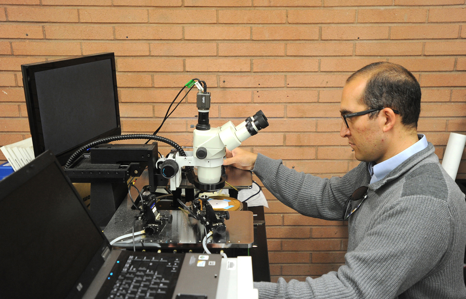 Moh El-Naggar, an assistant professor of physics at the University of Southern California, sits at the probe station where he made some of his discoveries involving biological electron transport among anaerobis bacteria. El-Naggar and other scientists at USC are doing basic research to determine how certain bacteria are able to transfer electrons great distances from themselves to other cells or inorganic minerals. Photograph by Kent Treptow for PBSNewsHour