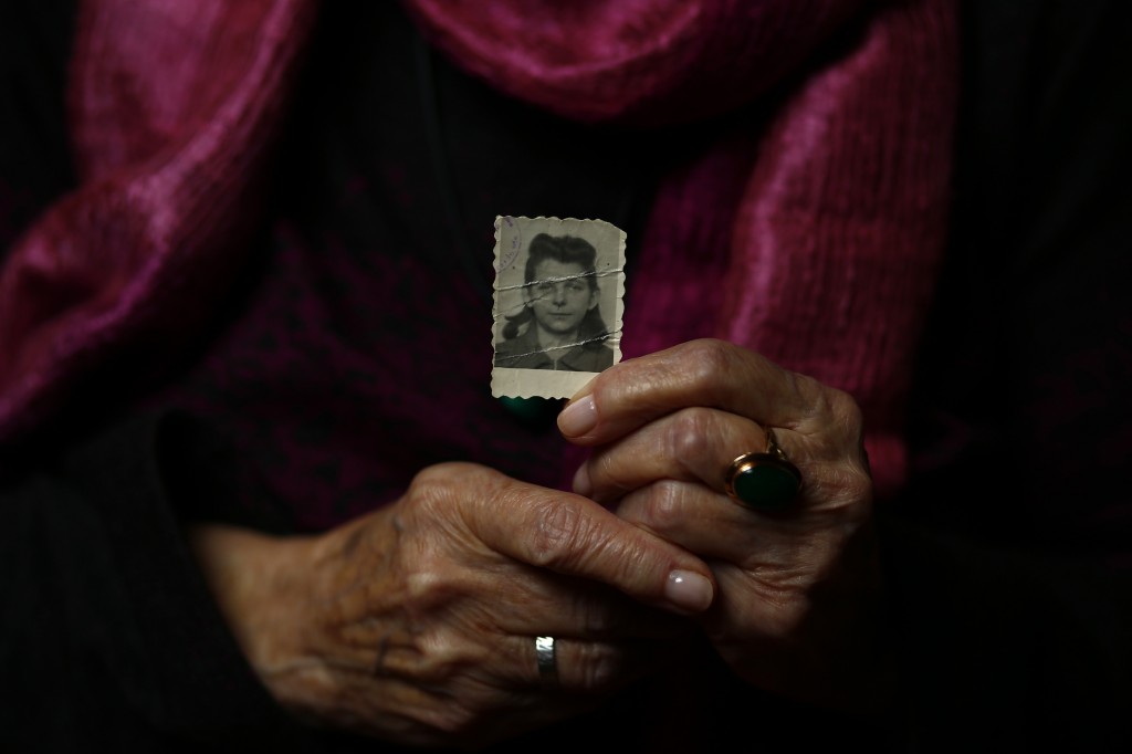 Auschwitz concentration camp survivor Halina Brzozowska holds a picture of herself during the war as she poses for a portrait in Warsaw
