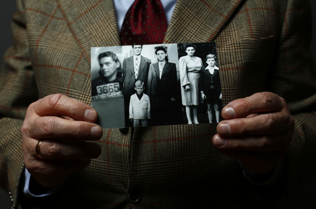 Auschwitz concentration camp survivor Jacek Nadolny holds up a wartime photo of his family in Warsaw