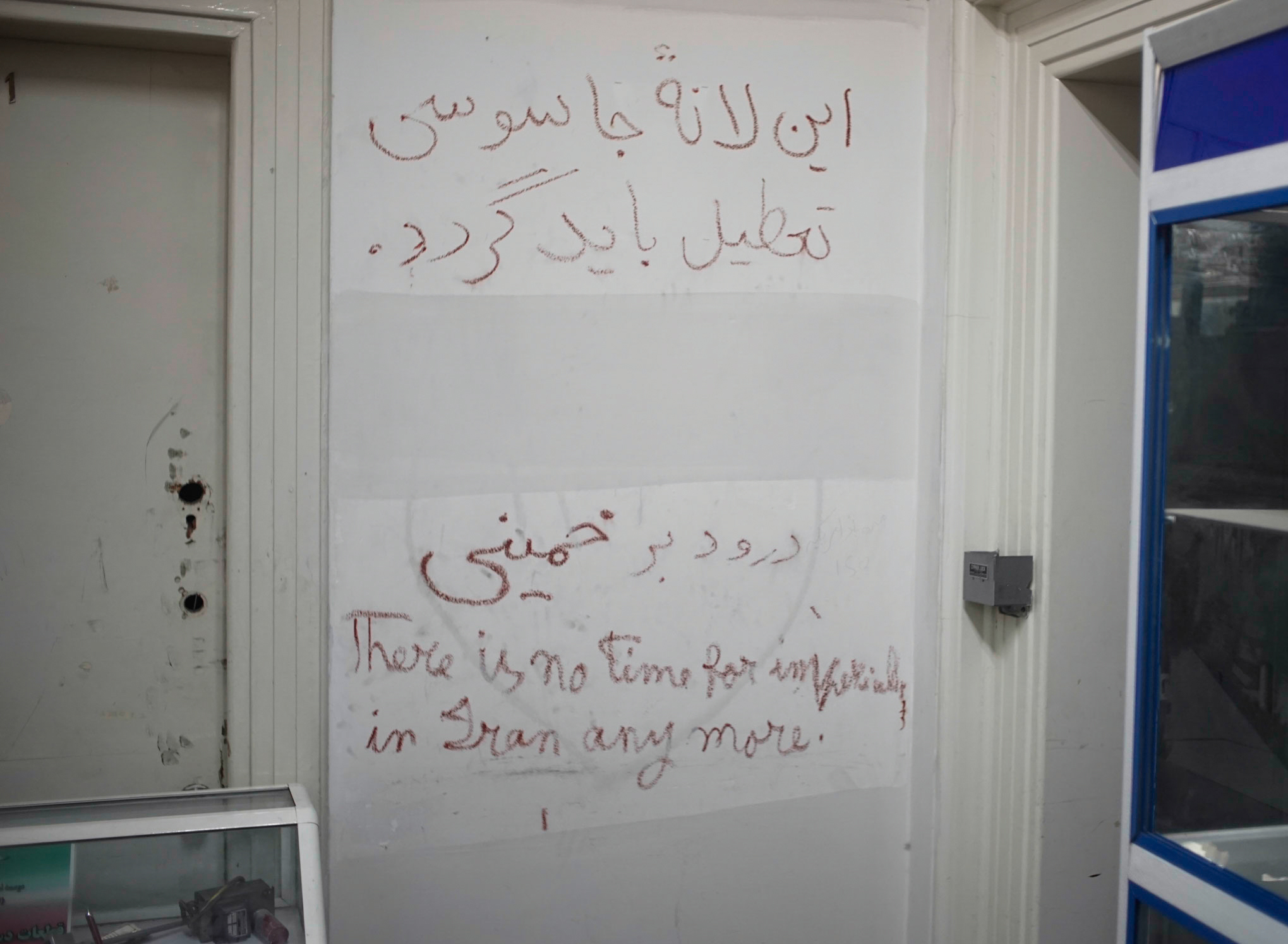 Grafitti on the walls inside the museum. The farsi words at the top read: “This den of spies must be shut.” At the bottom it says “Greetings to Khomeini.”