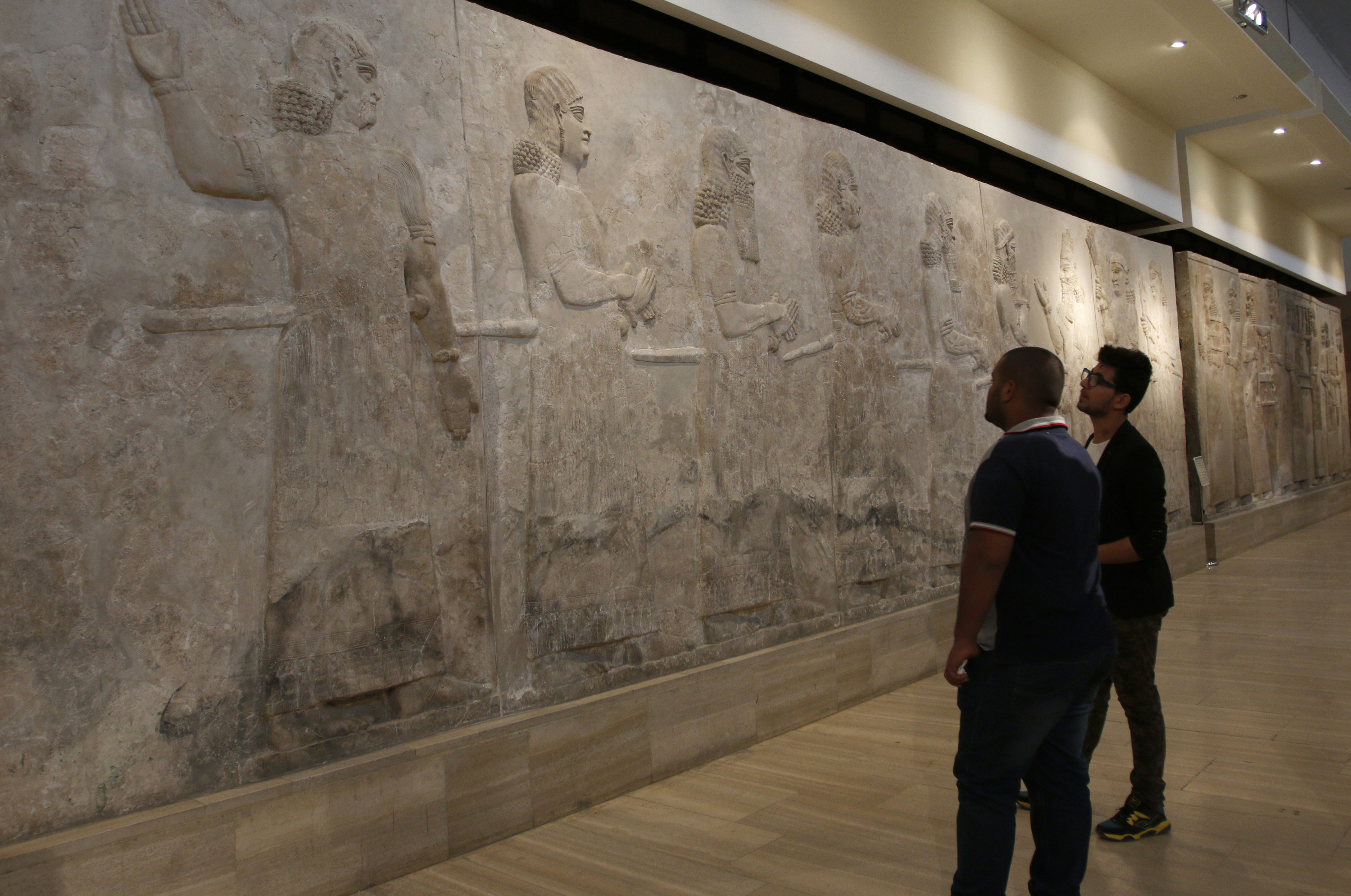 Visitors look at Assyrian mural sculptures at the Iraqi National Museum in Baghdad, March 8, 2015. Islamic State militants have desecrated Assyrian relics and ancient sites. Photo by Khalid al-Mousily/Reuters