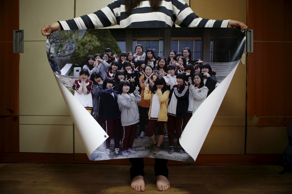 Eom Ji-yeong, mother of Park Ye-ji, a high school student who died in the Sewol ferry disaster, poses for a photograph with a picture showing her daughter (4rd L, in top line) with her schoolmates when she was 15, in her daughter's room in Ansan April 8, 2015. Her daughter's dream was to be a computer programmer. Photo by Kim Hong-Ji/Reuters