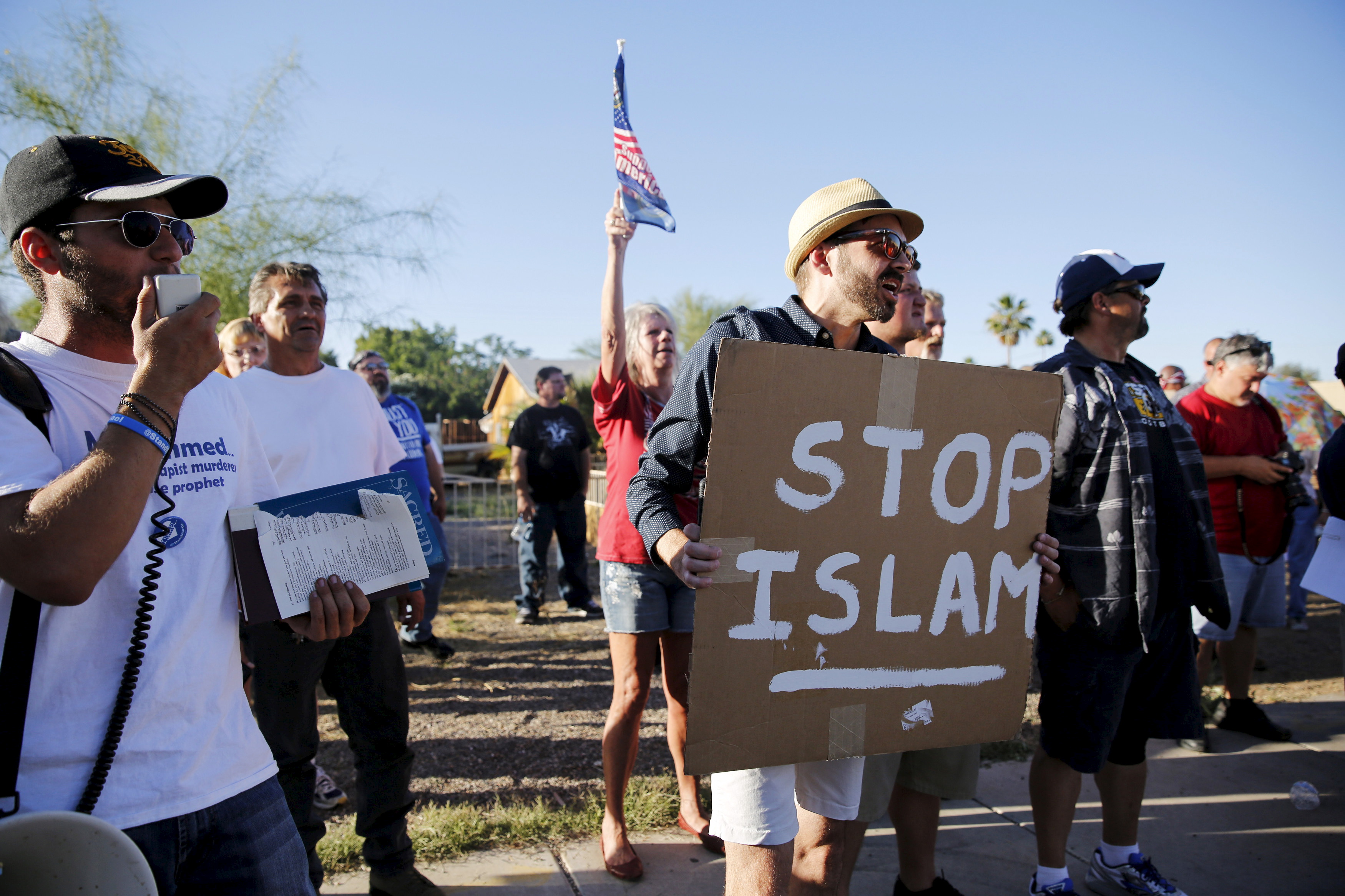 A demonstrator shouts and carries a "Stop Islam" sign while another rips pages out of a Quran during a "Freedom of Speech Rally Round II" outside the Islamic Community Center of Phoenix, Arizona on May 29, 2015. Photo by Nancy Wiechec/Reuters.