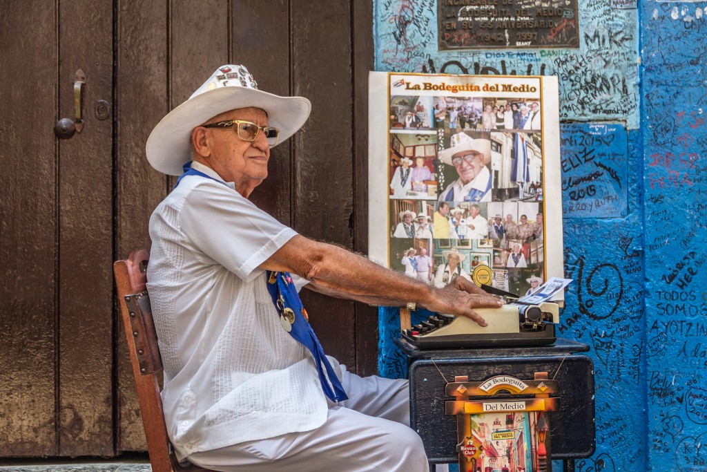 A poet sits outside La Bodeguita Del Medio, an Old Havana bar once frequented by Ernest Hemingway and Pablo Neruda. Photo by Frank Carlson