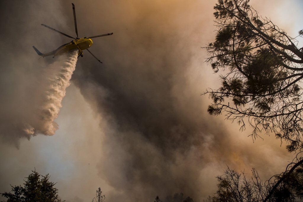 A helicopter drops water on the Rocky Fire in Lake County, California July 30, 2015. Photo by Max Whittaker/Reuters