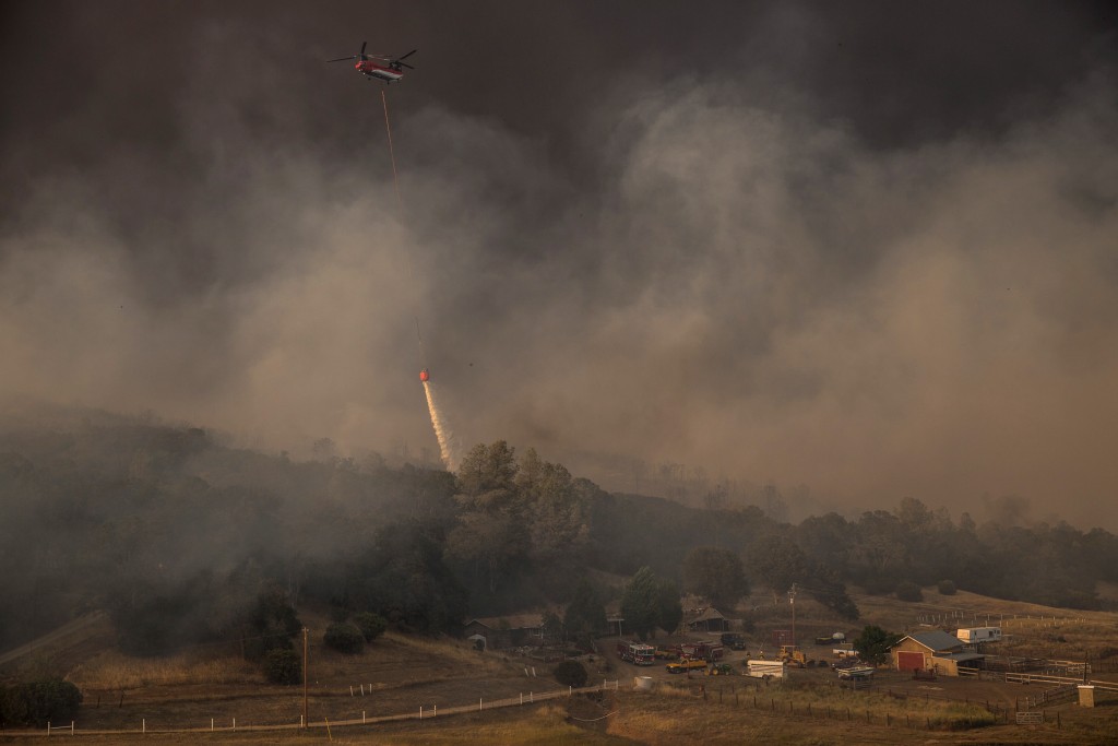 A helicopter drops water to protect a home from the rapidly moving Rocky Fire in Lake County, California July 30, 2015. Photo by Max Whittaker/Reuters