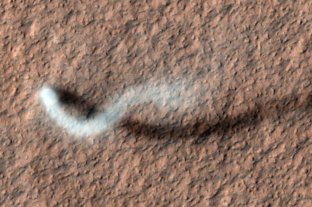 A towering dust devil on the Martian surface captured by the High Resolution Imaging Science Experiment (HiRISE) camera on NASA's Mars Reconnaissance Orbiter. This dust plume is more than half a mile in height and about 30 yards in diameter. Photo by NASA/JPL-Caltech/University of Arizona