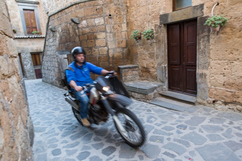 No cars are allowed in Civita di Bagnoregio due to the fragile nature of the landscape, so a man on a motorcycle must suffice for a garbage truck. Photo by Frank Carlson
