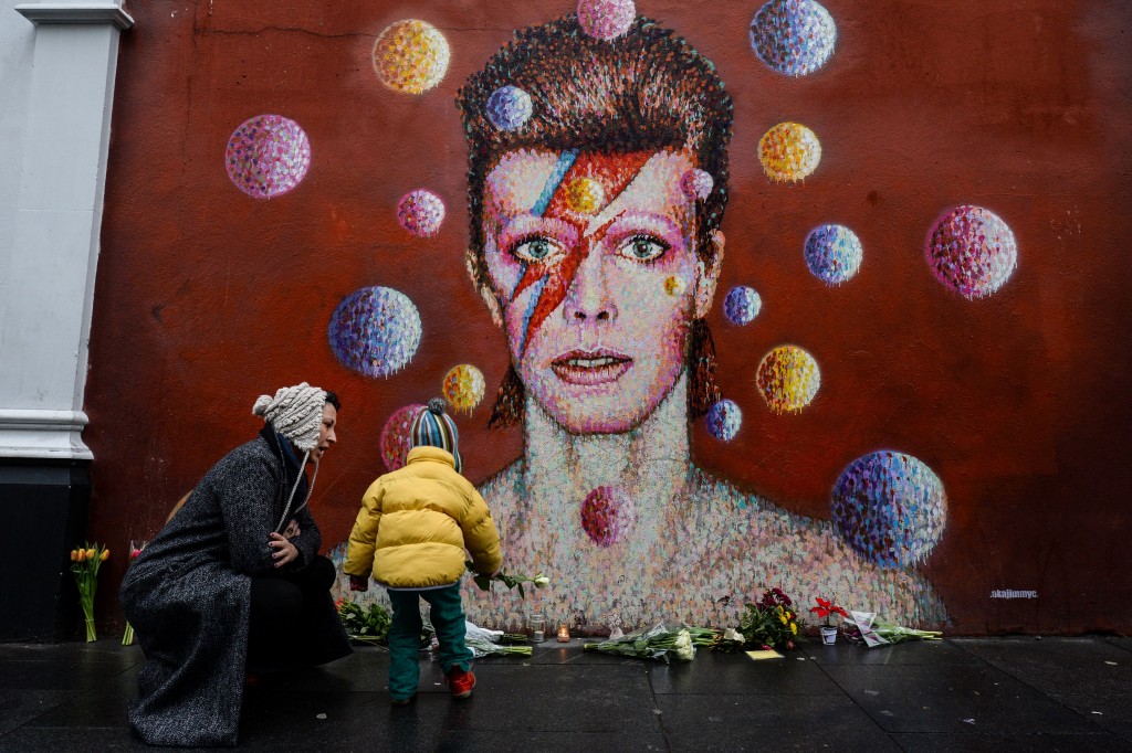 Floral tributes are left beneath a mural of David Bowie, painted by Australian street artist James Cochran, aka Jimmy C, following the announcement of the singer's death at age 69. Photo by Chris Ratcliffe/AFP/Getty Images