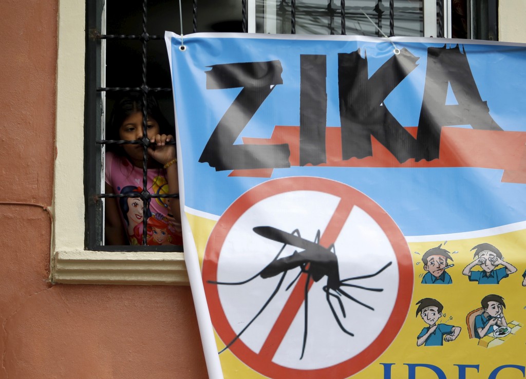 A woman looks on next to a banner as soldiers and municipal health workers take part in cleaning of the streets, gardens and homes as part of the city's efforts to prevent the spread of the Zika virus vector, the Aedes aegypti mosquito, in Tegucigalpa, Honduras. Photo by Jorge Cabrera/Reuters