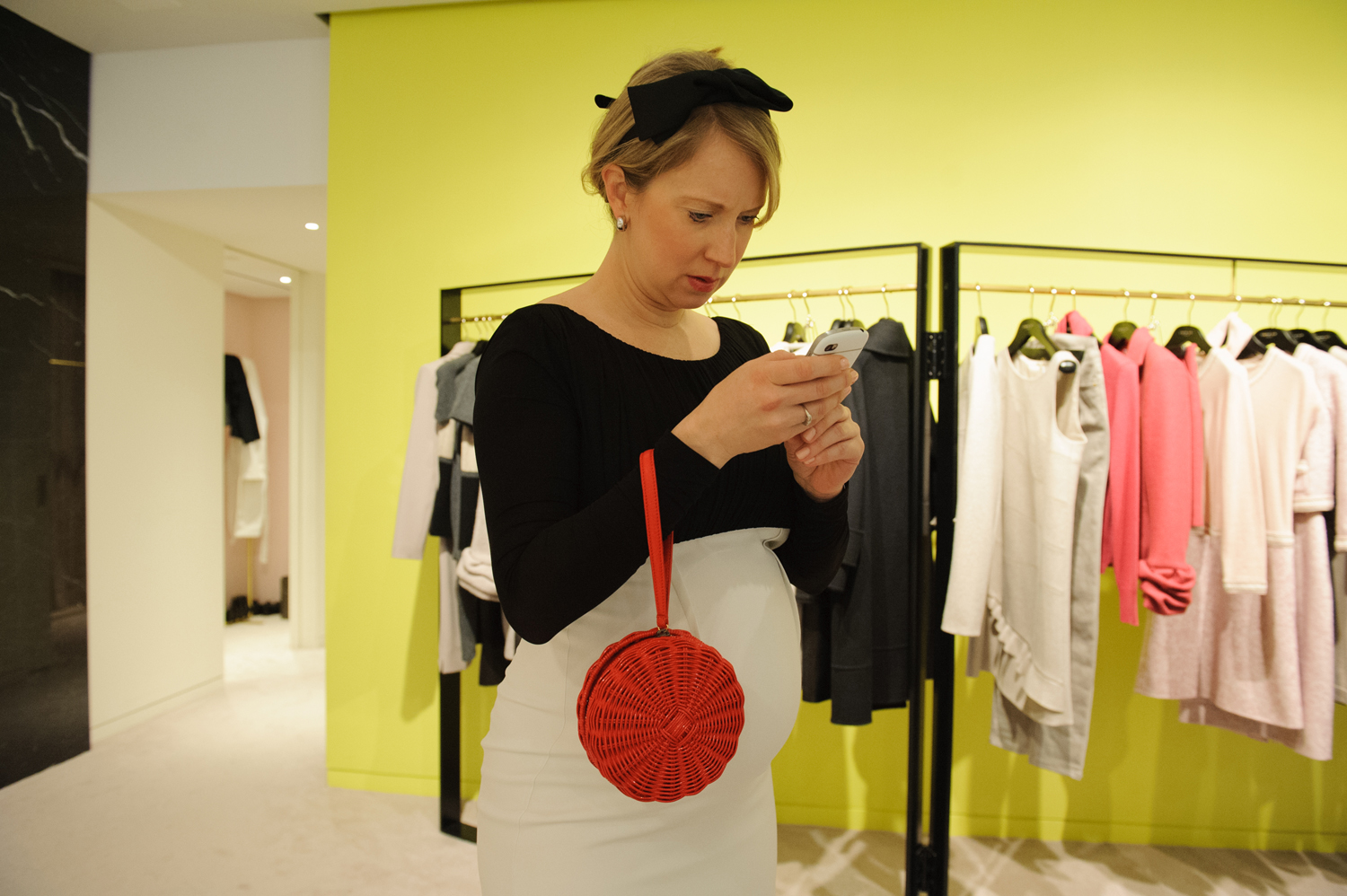 Pregnant Assistant District Attorney Lucy Lang checks her work email while trying on a dress to wear to the Frick Collection Young Fellows Ball. She serves on the museum's Young Fellows Steering Committee and helped to plan the ball.