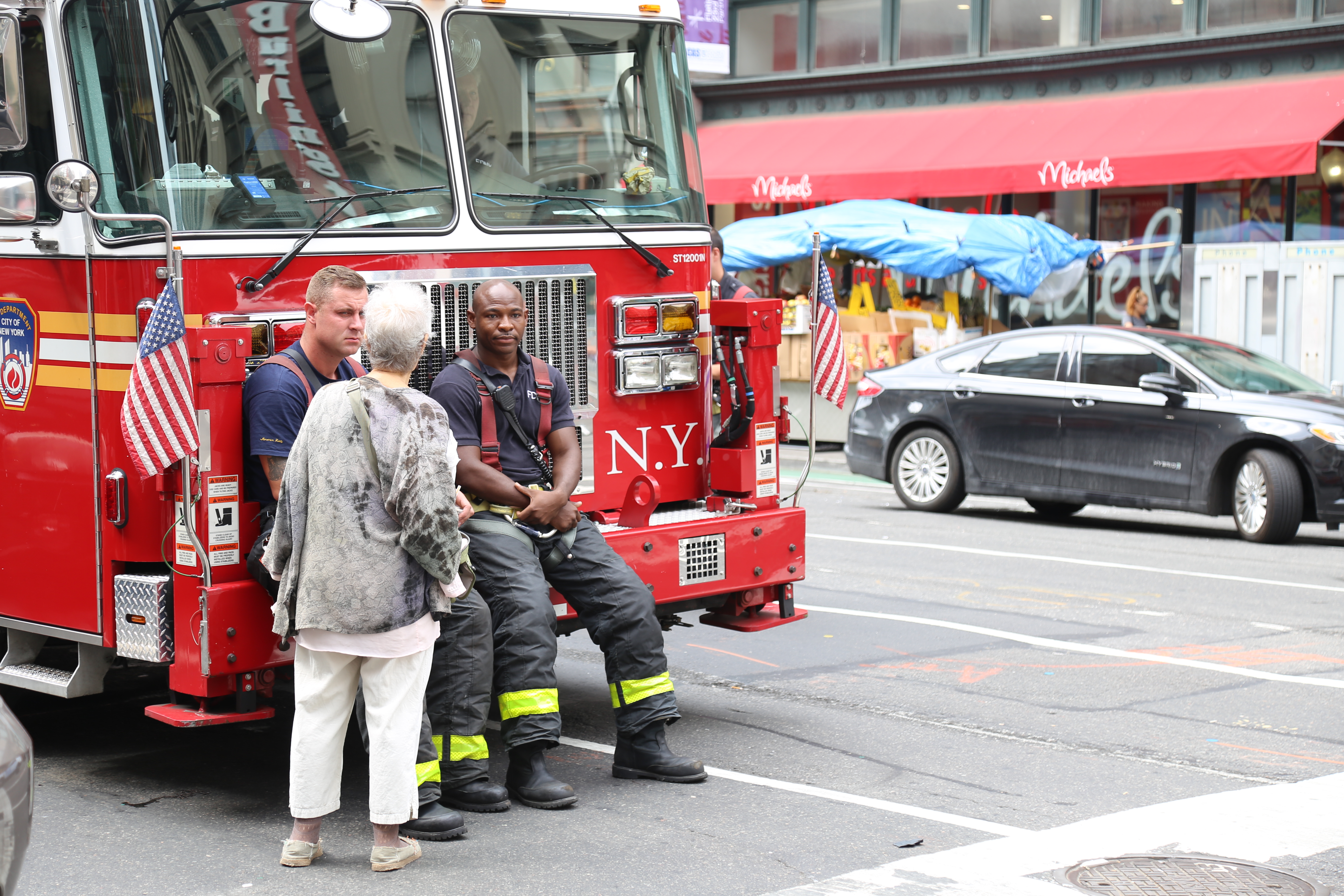 Two members of the New York City Fire Department's Tower Ladder 12 sit stationed on Sunday near the intersection of 6th Avenue and 22nd Street. Photo By Michael D. Regan/PBS NewsHour