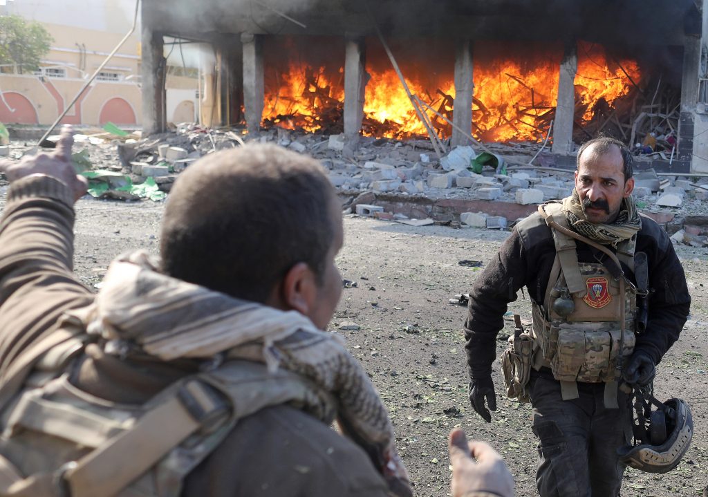 An Iraqi special forces soldier gestures in front of a burning house after an Islamic State suicide car bomb attack at Iraqi special forces during clashes in Mosul, Iraq. Photo by Goran Tomasevic/Reuters
