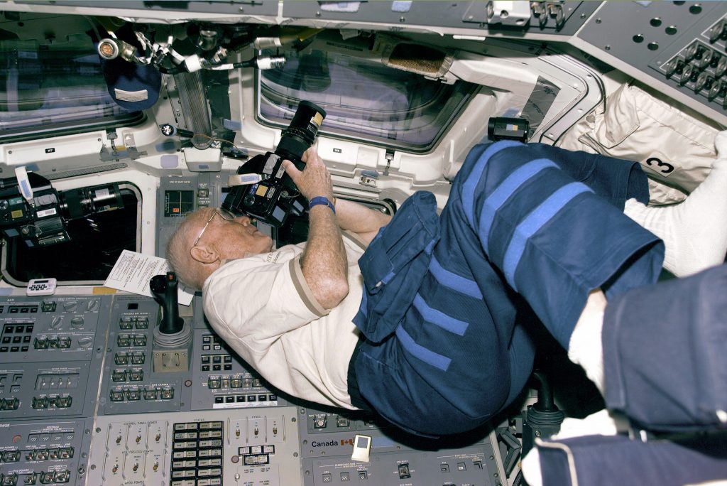 Astronaut and U.S. Senator John Glenn positions himself to take photos from the Discovery's aft flight deck windows on October 30, 1998. Photo courtesy NASA.