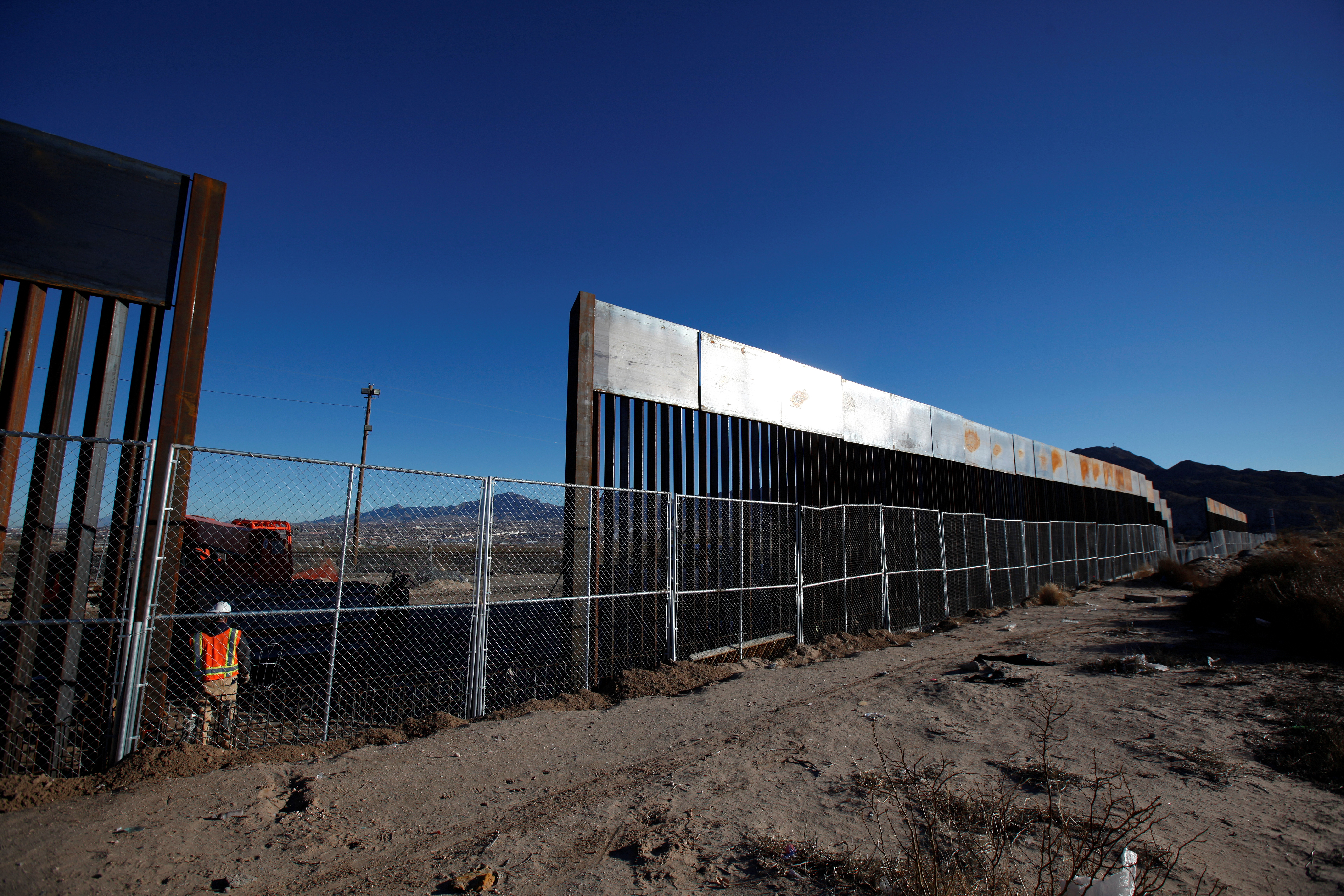 A worker stands next to a newly built section of the U.S.-Mexico border fence at Sunland Park, New Mexico, opposite Ciudad Juarez, Mexico. Photo by Jose Luis Gonzalez/Reuters