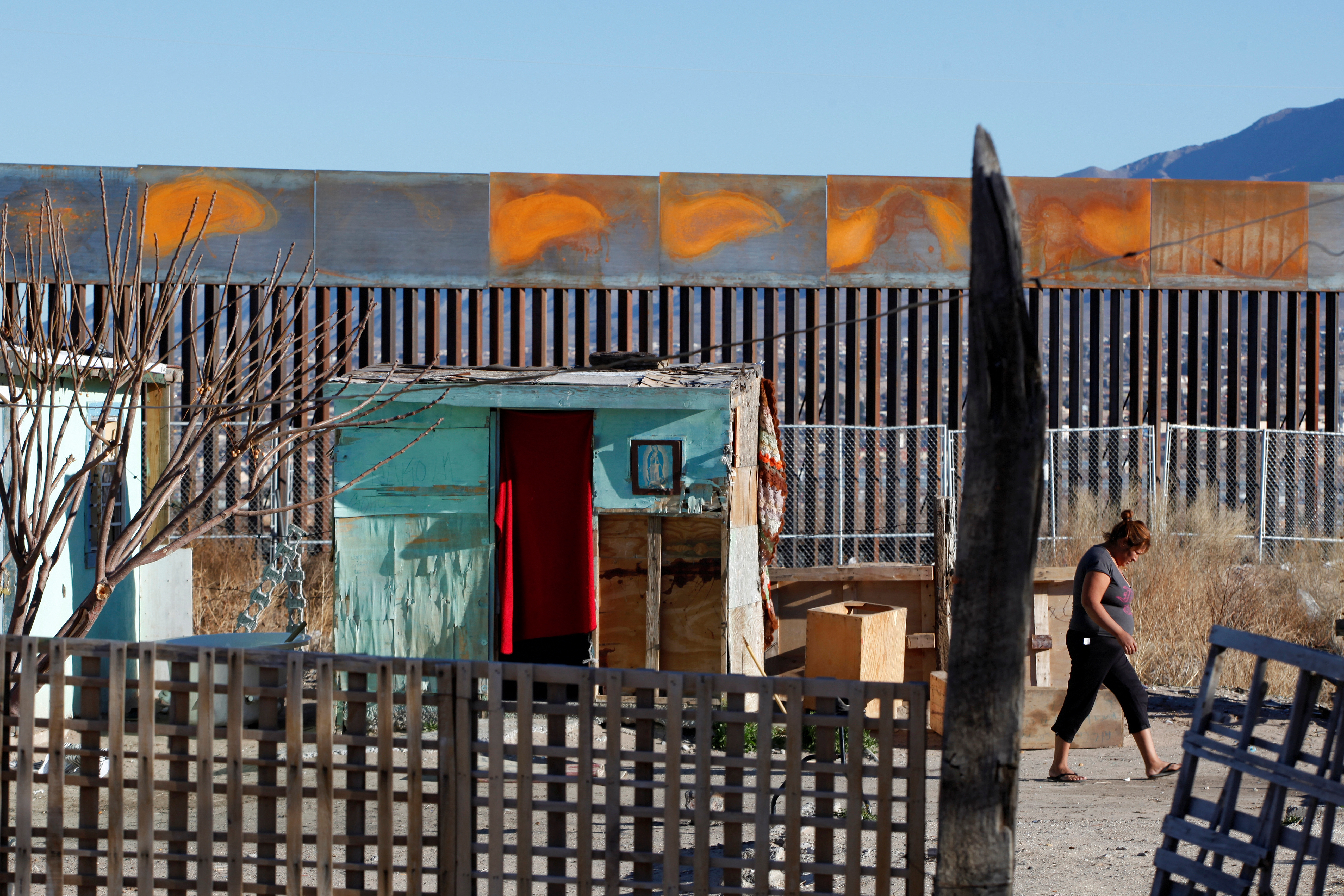 A woman walks across the patio of her house at a newly built section of the U.S.-Mexico border fence in Ciudad Juarez, Mexico. Photo by Jose Luis Gonzalez/Reuters