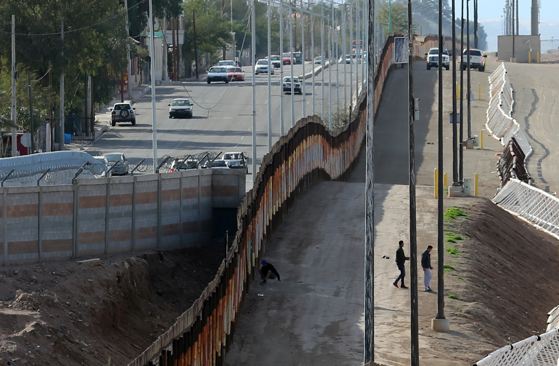 Three men jump the fence from Mexico and give themselves up to U.S. border patrol agents in Calexico, California. Photo by Mike Blake/Reuters