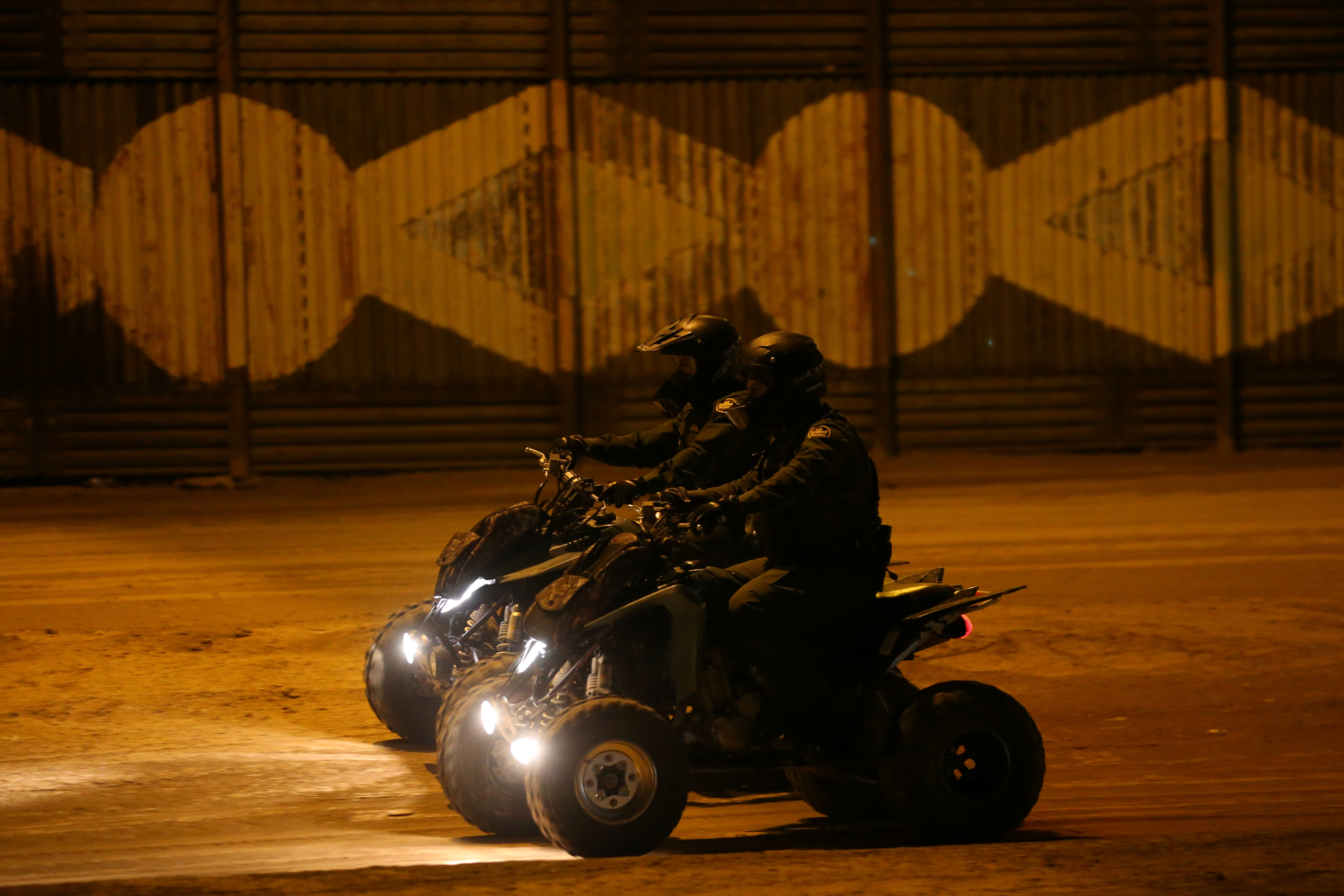 U.S. border patrol agents ride along the border wall next to Mexico in Calexico, California on Feb. 8. Photo by Mike Blake/Reuters