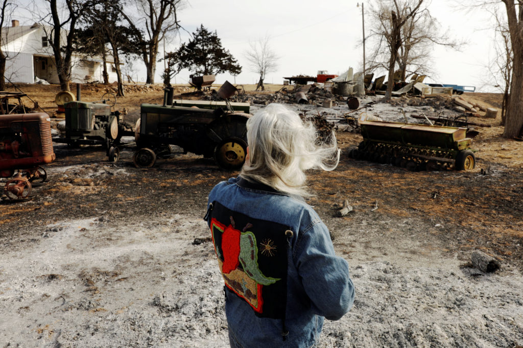 Kay Rottmayer, 65, looks at farm equipment that was destroyed by wildfires near Knowles, Oklahoma, U.S., March 14, 2017. REUTERS/Lucas Jackson SEARCH "JACKSON WILDFIRE" FOR THIS STORY. SEARCH "WIDER IMAGE" FOR ALL STORIES. - RC1534079F00