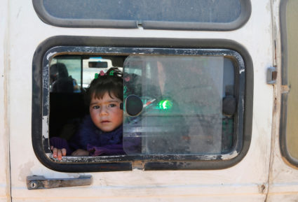 A child looks out of a window as Syrian refugees prepare to return to Syria from the Lebanese border town of Arsal, Lebanon. Photo by Mohamed Azakir/Reuters