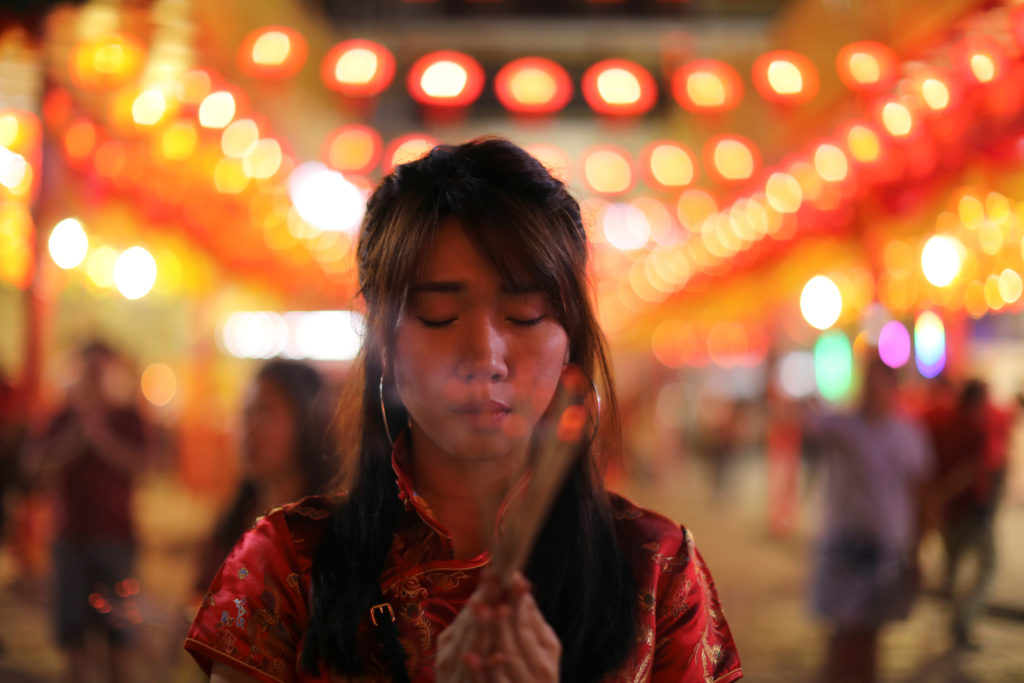 A woman lights incense while praying in a Chinese temple during the celebration of the Lunar New Year in Chinatown in Bangkok, Thailand on February 4, 2019. Photo by Jorge Silva/Reuters