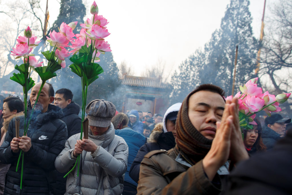 People burn incense sticks and pray for good fortune at Yonghegong Lama Temple on the first day of the Lunar New Year of the Pig in Beijing. Photo by Thomas Peter/Reuters