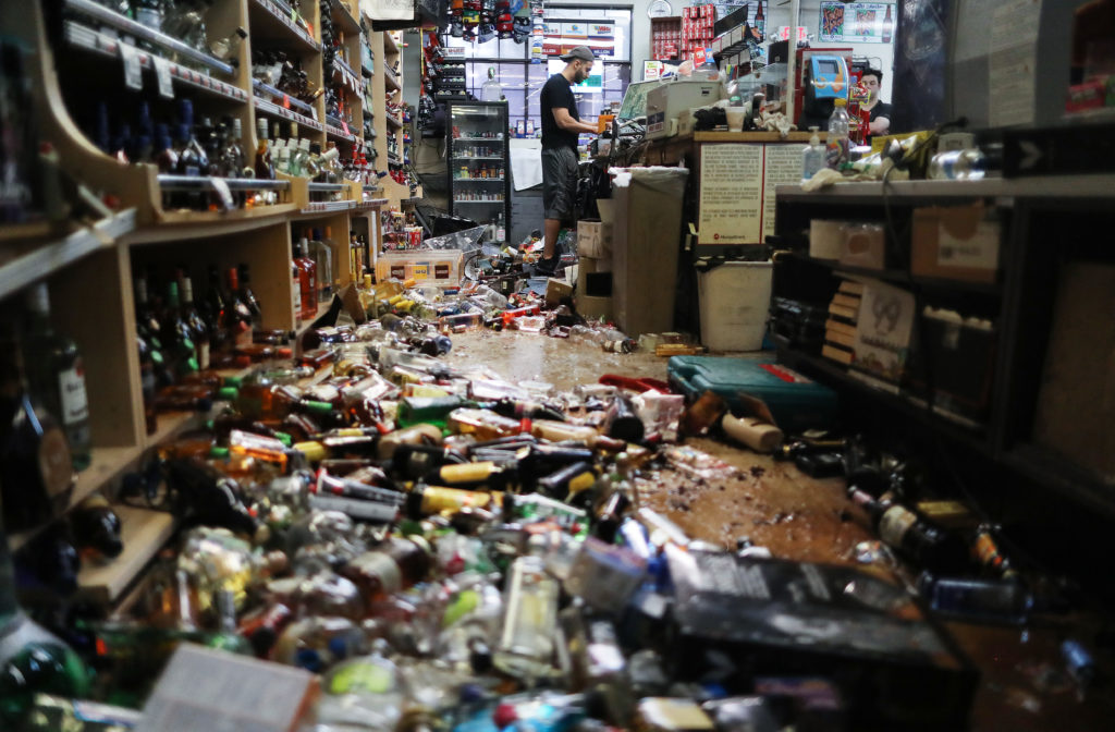 An employee works at the cash register at Eastridge Market, near broken bottles scattered on the floor, following a 7.1 magnitude earthquake which struck in the area, on July 6, 2019 in Ridgecrest, California. The earthquake, which occurred July 5th, was the second large earthquake to hit the area in two days and the largest in Southern California in 20 years. The store has remained open since the 7.1 earthquake struck in an effort to serve the community. Photo by Mario Tama/Getty Images