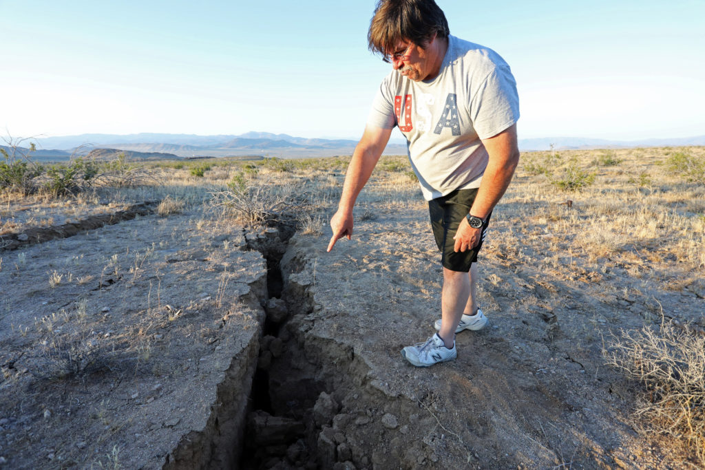 A man looks into a fissure that opened in the desert during a powerful earthquake that struck Southern California, near the city of Ridgecrest, California, U.S., July 4, 2019. Photo by REUTERS/David McNew