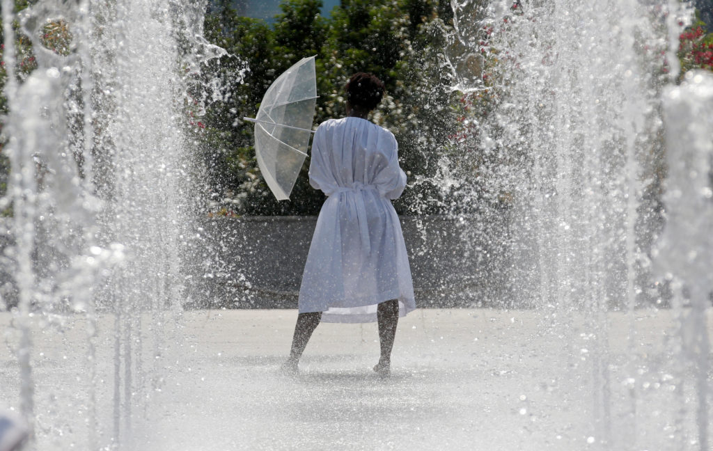 A woman cools off in water fountains in a park as hot summer temperatures hit Paris, France, June 22, 2017. Photo by REUTERS/Jean-Paul Pelissier