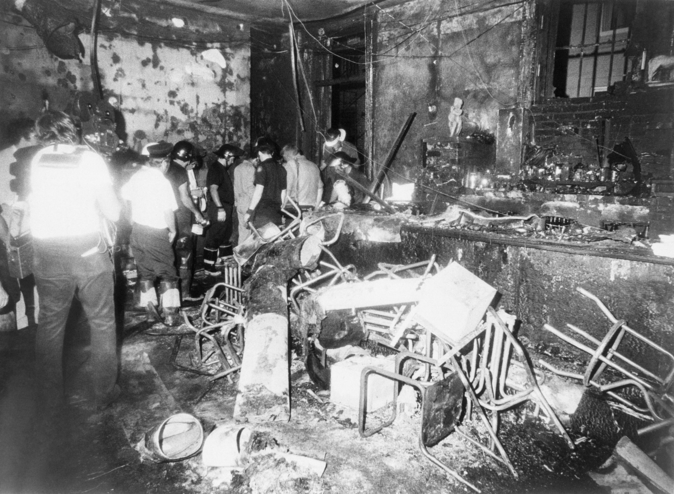 Firemen walk through the charred ruins of the Upstairs Bar