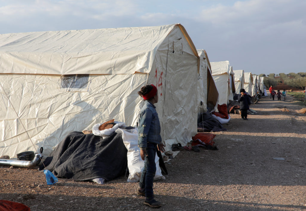 Children stand outside tents erected for people affected by a devastating earthquake, in Jandaris