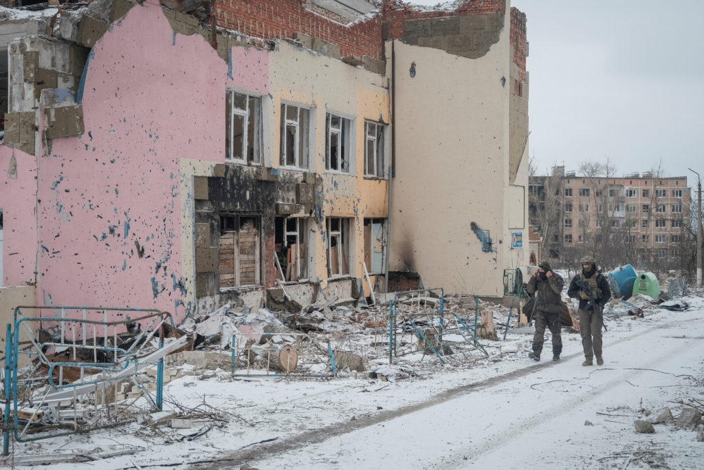 Ukrainian servicemen walk an empty street near buildings damaged by a Russian military strike in the front line city of Vu...