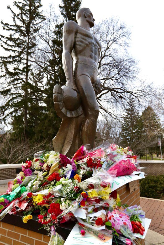 Flowers left at the Michigan State University (MSU) “Sparty” statue the day after a mass shooting on campus killed three students and injured five students, East Lansing, Michigan, Feb. 14, 2023. Photo by Campbell Berg.