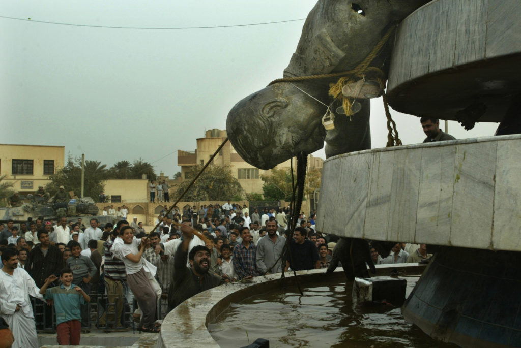 Iraqi citizens hit a pulled down a statue of Saddam Hussein in the town of Karbala, on the 18th day of the war in Iraq, 2003. Photo by Peter Andrews PA/CMC/REUTERS