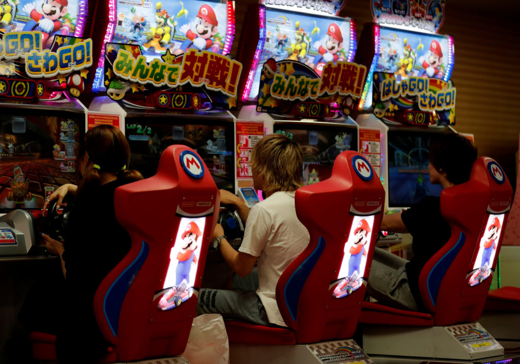 People play Mario Kart Arcade GP DX game at Tatio's game center in Tokyo
