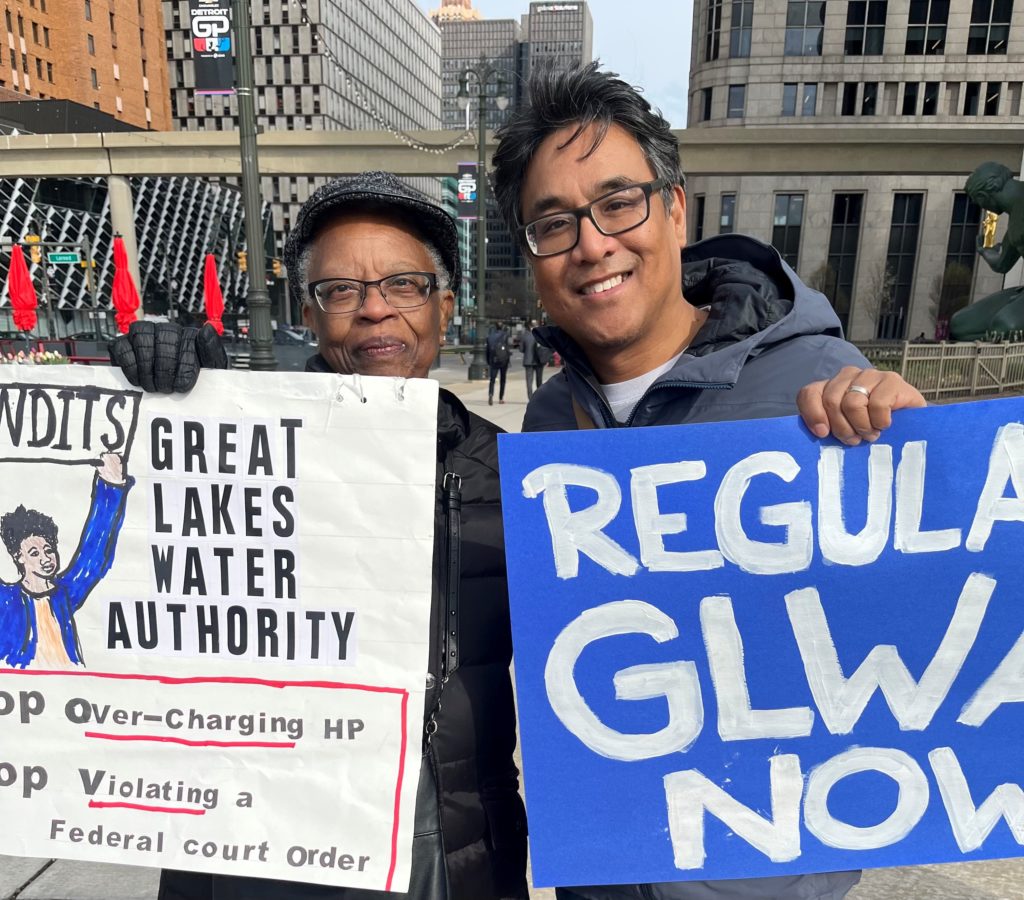 Two protesters holding signs protesting the Great Lakes Water Authority overcharging the City of Highland Park for water and sewerage in Highland Park, Michigan, April 21, 2023. 