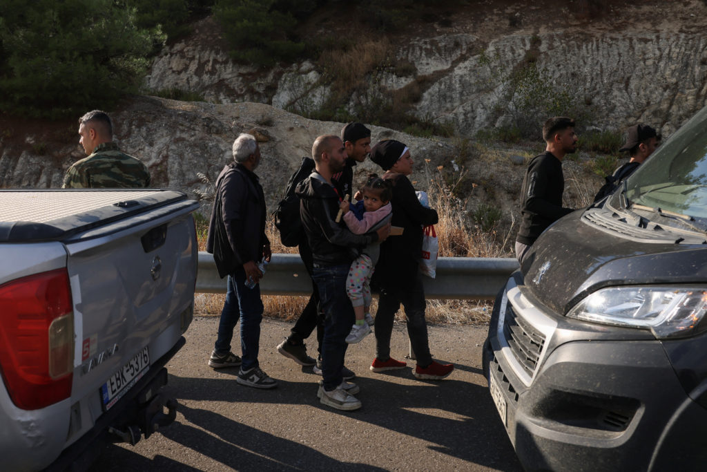 Syrian refugees flee a wildfire burning in the region of Evros