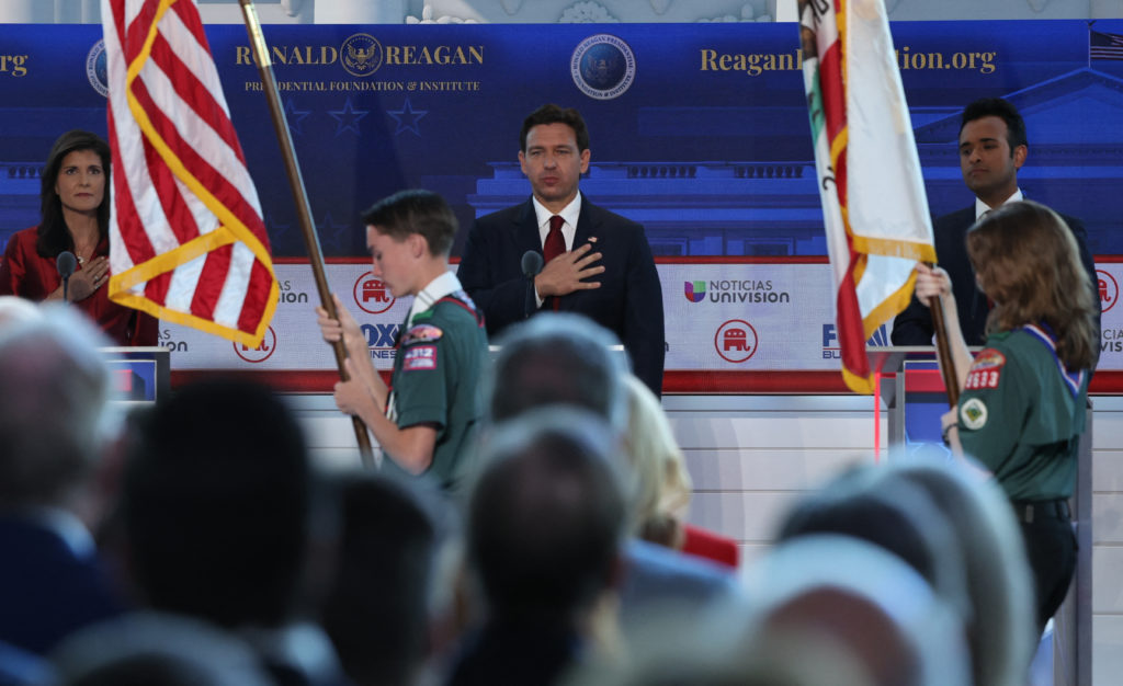 Former South Carolina Governor Nikki Haley, Florida Governor Ron DeSantis and former biotech executive Vivek Ramaswamy hold their hands over their hearts as Boy and Girl Scouts march past with the flags of the United States and California before the start of of the second Republican candidates' debate of the 2024 U.S. presidential campaign at the Ronald Reagan Presidential Library in Simi Valley, California, U.S. September 27, 2023. Photo by Mike Blake/REUTERS