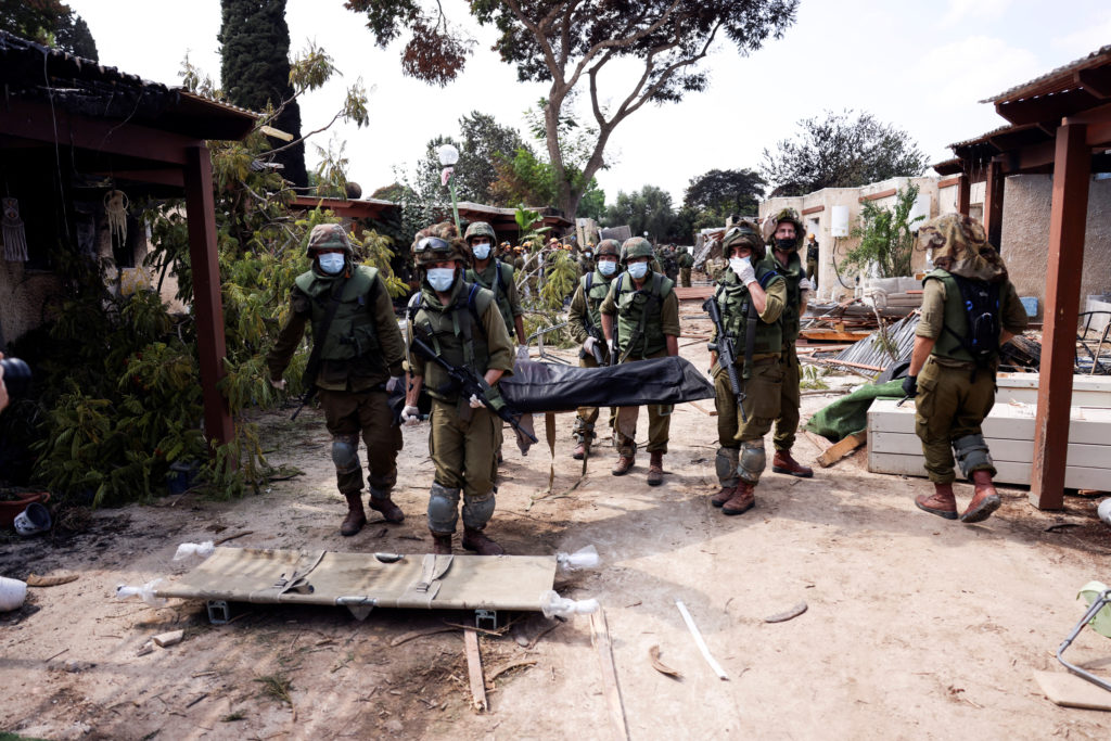 Israeli soldiers carry the body of a victim of an attack by militants from Gaza at Kibbutz Kfar Aza, in southern Israel