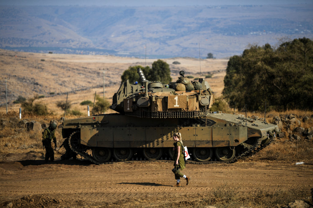 An Israeli soldier walks past a tank amid heightened tensions between Israel and Lebanon, as seen from the border with Leb...