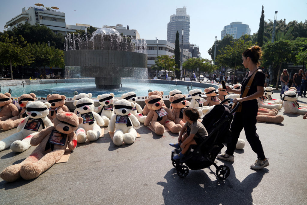 A woman and child look at teddy bears, each representing children who are believed to be held hostage in Gaza, in Tel Aviv