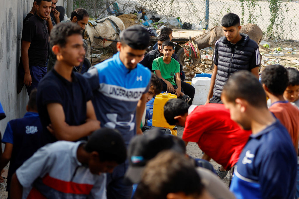 Palestinians collect water, amid a lack of clean and drinking water, as the conflict between Israel and Hamas continues, i...