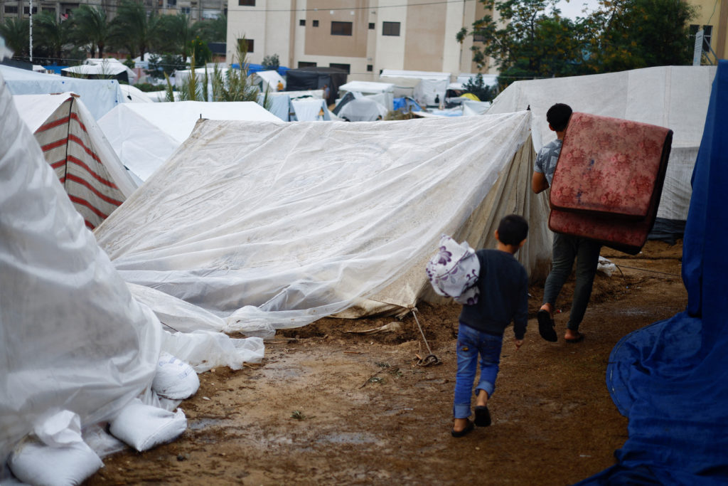 Palestinian children walk next to tents following a rainfall, amid the ongoing conflict between Israel and Palestinian Isl...