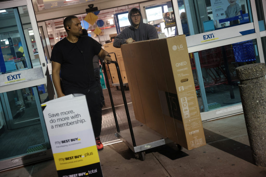 Employee at Best Buy electronics store helps to move out a television after a shopper made a purchase during Black Friday ...