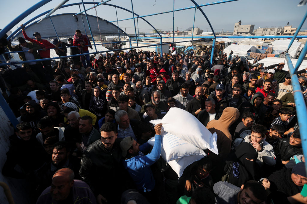 Palestinians receive flour bags distributed by UNRWA during a temporary truce between Hamas and Israel, in Khan Younis